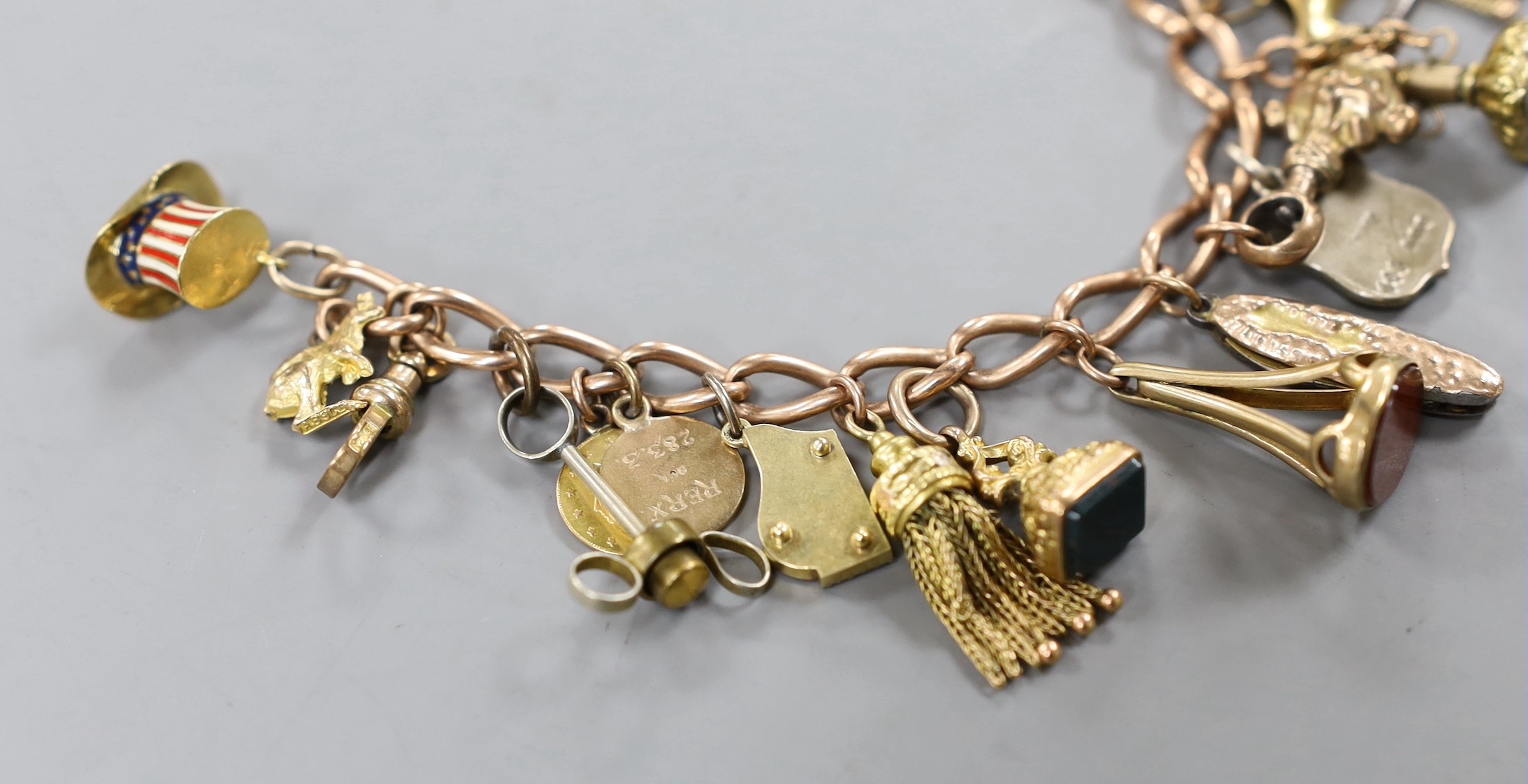 A 9ct charm bracelet, hung with assorted charms including two 9ct, silver and enamel, gilt metal and two gold coins gross weight 61.4 grams.